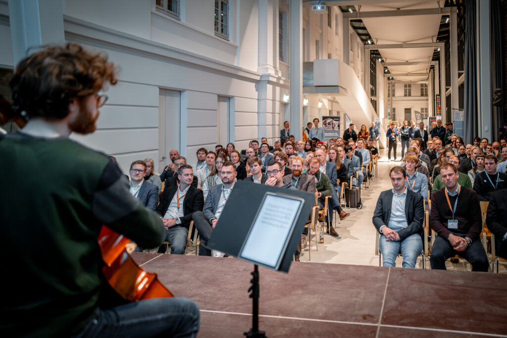 Musikalischer Bühnenmoment vor vollbesetzten Sitzreihen in der Veranstaltungshalle.